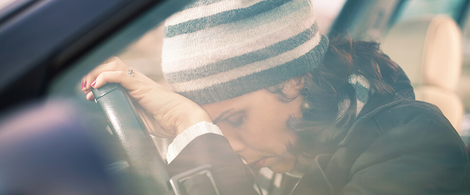 Woman with head on steering wheel in shock